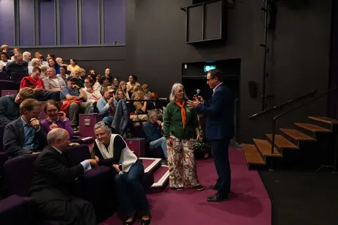 A speaker standing beside the tiered seating while the audience listens
