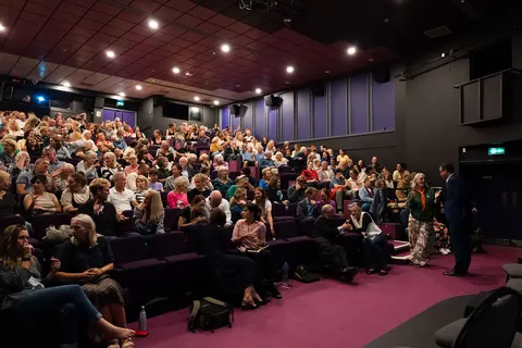 A packed auditorium of people seated in rows, seen from the front