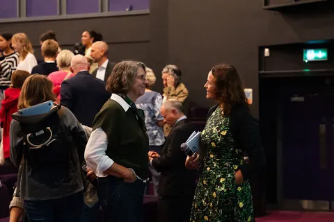 People standing in the aisle among the seats, talking in the auditorium