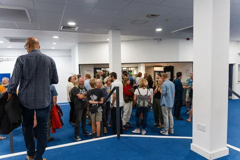People standing and talking in the bright foyer with its blue carpet
