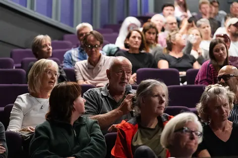 Seated audience members close up, listening to a speaker