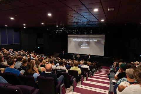 A wide view of a full auditorium with the screen in the distance